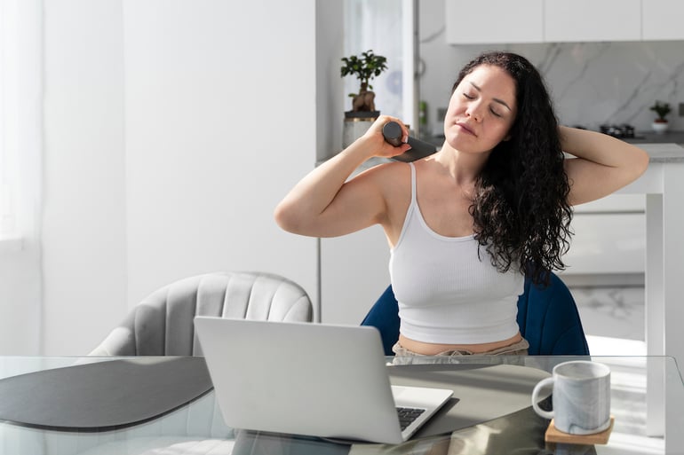 mujer dandose masaje mientras trabaja en casa