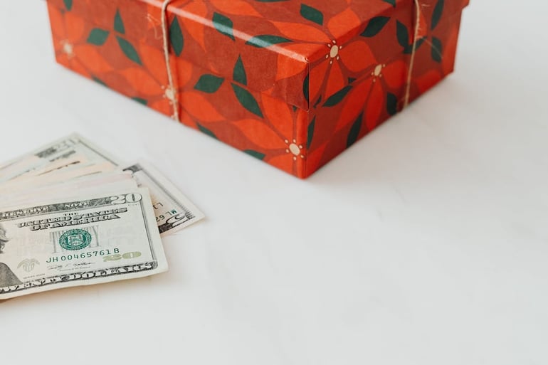 caja de regalo navideña con dinero a un lado