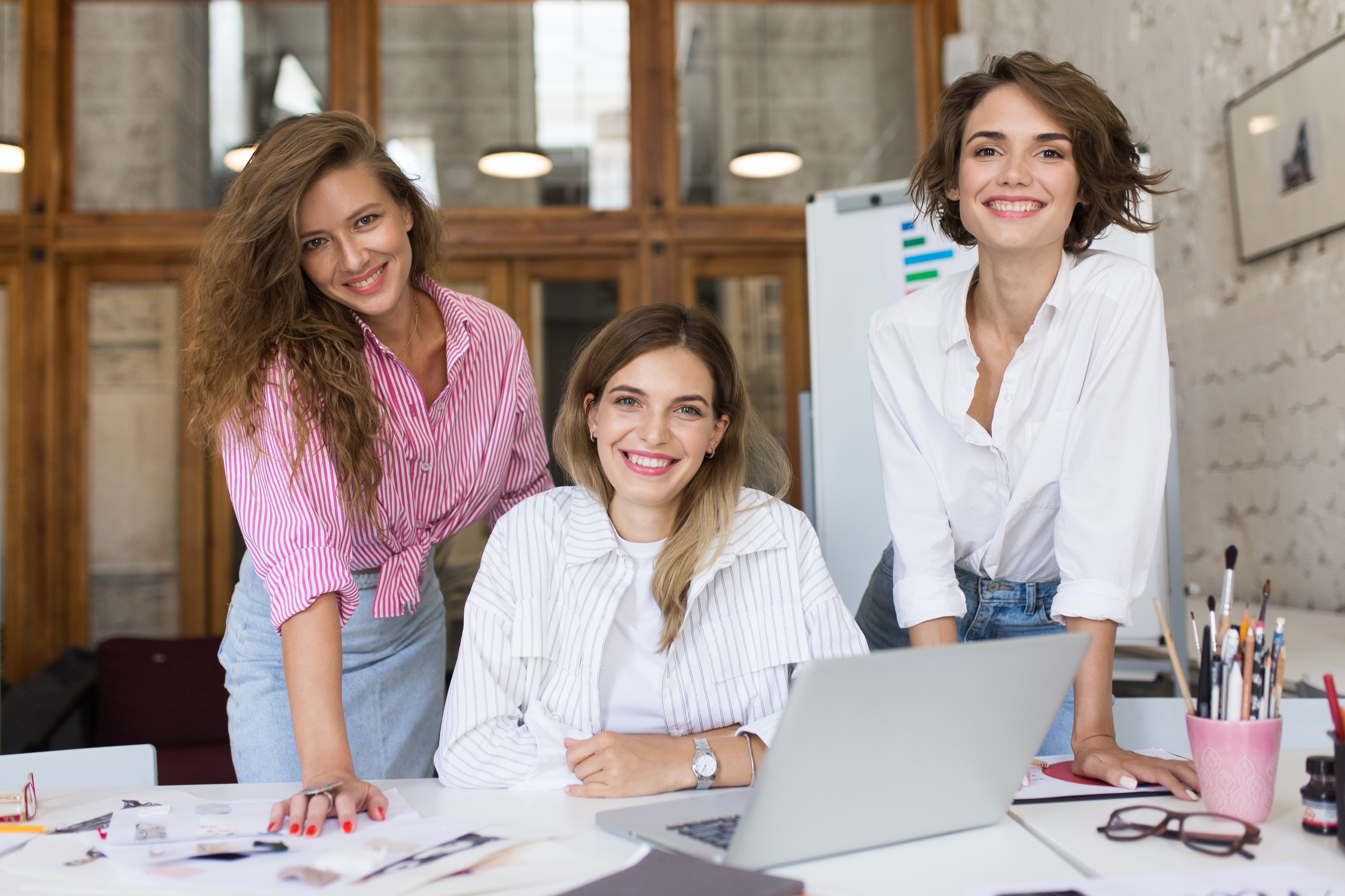 group-young-cheerful-women-with-laptop-happily-looking-cam